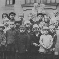 Фотография во дворе дома на фоне корпуса художественных мастерских. Тамара Кузнецова стоит справа от мальчика с мячом в шляпке и в пальто с крупными пуговицами. Предположительно автор фотоснимка отец Тамары Иван Макарович Кузнецов. По воспоминаниям Натальи Саркисьянц, он увлекался фотографией. 13 мая 1931 года